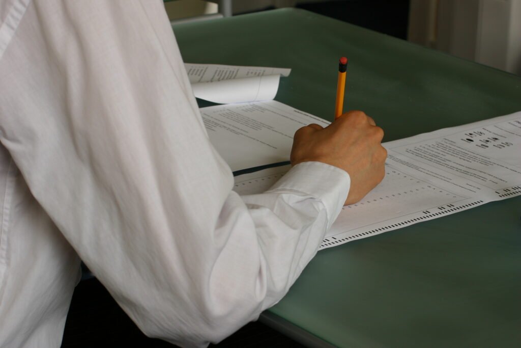 Student writing an exam paper in a classroom